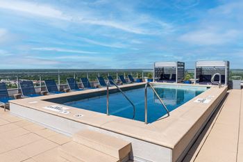 A large outdoor swimming pool with lounge chairs and a view of the horizon at Two Twelve Clayton Apartments, Missouri